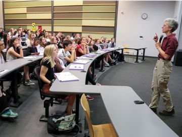 A person standing in front of a lecture hall teaching a class